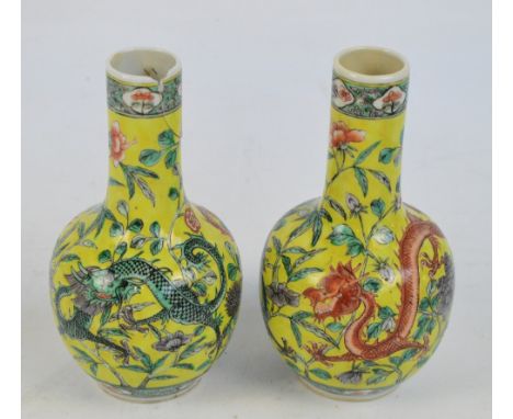 A pair of c.1900 Chinese bottle vases painted in enamel with chasing dragons amongst chrysanthemum and peony sprays on yellow