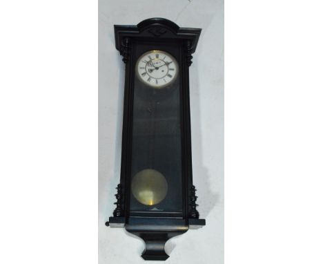 A late 19th century ebonised Vienna style twin weight wall clock with white enamel dial set with Roman numerals, length 99cm.