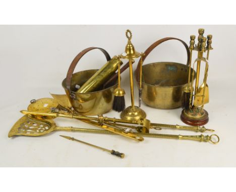 A collection of brassware including two fireside companion sets, jam pans, toasting fork, shell case, etc.