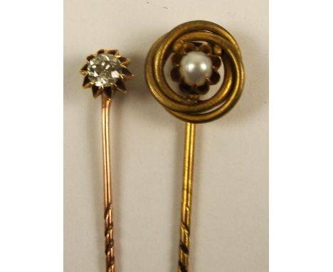 A yellow metal stick pin set with a single circular diamond weighing approximately 0.50cts, and a further stick pin centred w