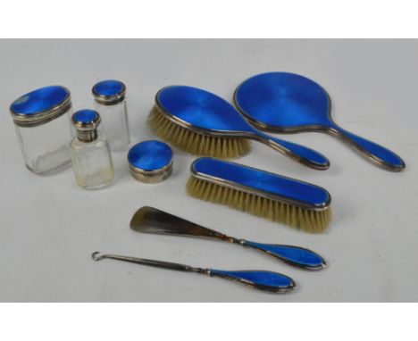 A George V hallmarked silver backed and blue guilloche enamel decorated nine piece dressing table set comprising a hand mirro