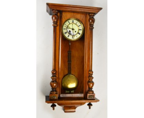 A late 19th century walnut Vienna style spring driven wall clock with circular dial set with Roman numerals flanked by pilast
