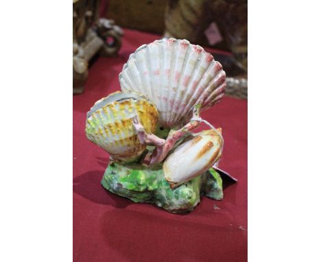 A 19th Century majolica menu holder, formed as bivalve shells on a rocky base. 6' high. C.R. Slight chips and losses to glaze