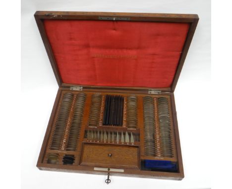 A wooden cased near-complete 'Opthalmic Optician' lense set with cushion interior and gilt lettering, 17ins wide (43cms)
