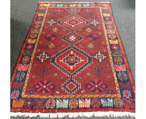 A hand-woven Iranian Yslem carpet, in ox-blood red ground  57 x 89ins (145 x 226cms)