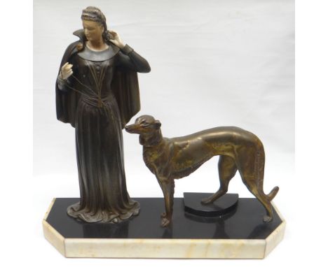 A French Art Deco painted spelter and ivorine sculpture of a standing lady in long dress and cloak and beside her lurcher dog