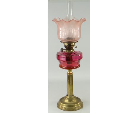 ANTIQUE CORINTHIAN COLUMN BRASS BASED OIL LAMP, cranberry glass reservoir, pink tinted etched glass shade, 68cms high