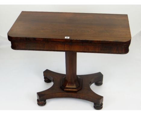 ANTIQUE ROSEWOOD FOLD-OVER CARD TABLE, faceted support on a shaped base with four bun feet, the top opening to reveal a repla