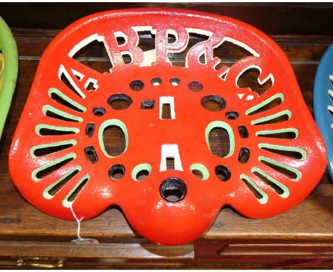 A pierced and cats iron tractor seat titled ABP &amp; Co, painted in red, green &amp; black, 36.5 x 39cm