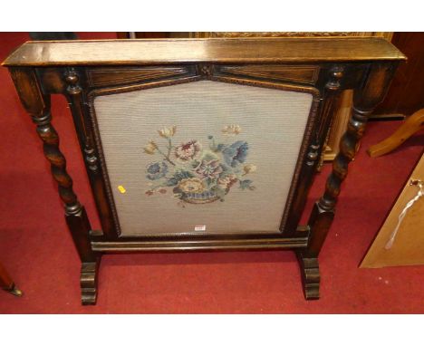 An early 20th century oak and floral needle work inset fire screen having spiral turned and square cut columns, width 78.5cm