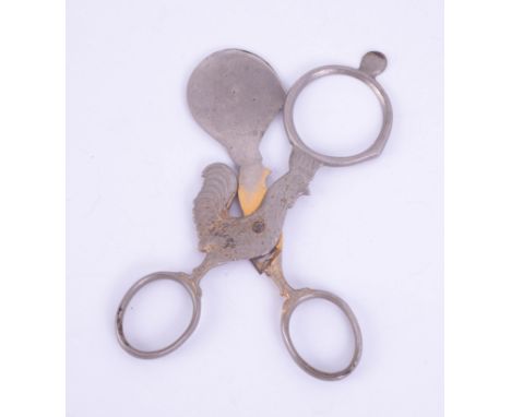 A vintage egg topper in the form of scissors with a cockerel.