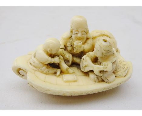 19th century Japanese ivory Netsuke of three figures on a boat reading, drinking and playing the lute, L5cm 