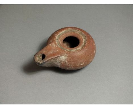 Greek, ceramic oil lamp, 5th century BC. Projecting nozzle with rounded end; bulbous body with indented rim and wide filling 