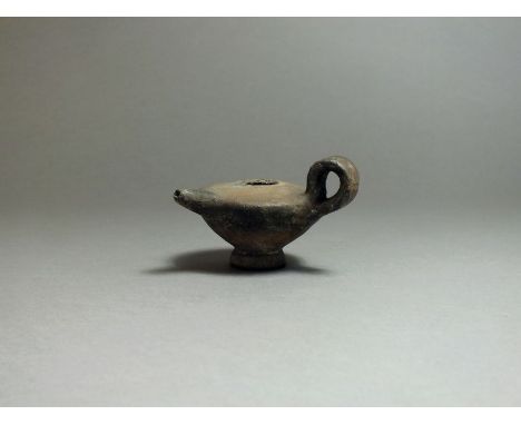 Greek, ceramic oil pourer, 5th century BC. Flat top with short nozzle to front, looped handle to side; small stem base