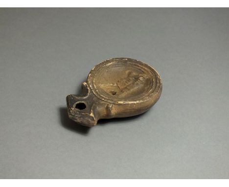 Roman, ceramic oil lamp, 2nd century AD; angled nozzle with petta pattern to either side; oval body with dished top decorated
