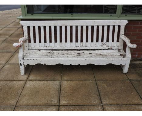 A painted wood garden bench, 19th century, with canted slat back and seat between out curved scroll arms over a shaped apron 