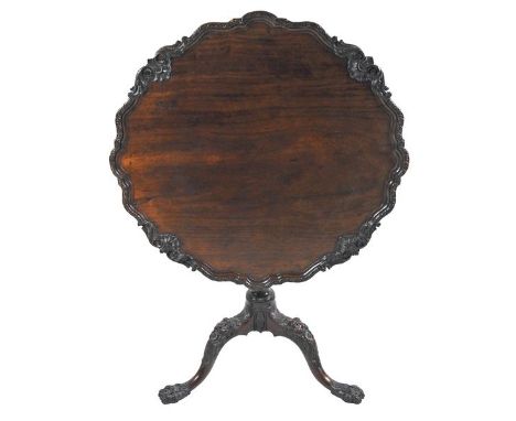 A George III mahogany pie crust top tripod table, the shaped tilt top with foliate and shell carved raised edge on a wrythen 