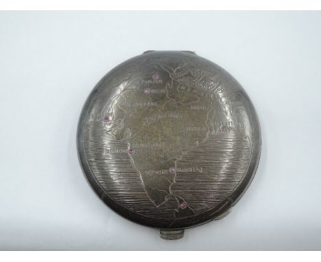 A white metal powder compact stamped silver having Indian map engraved to front with seven inset ruby chips marking major tow