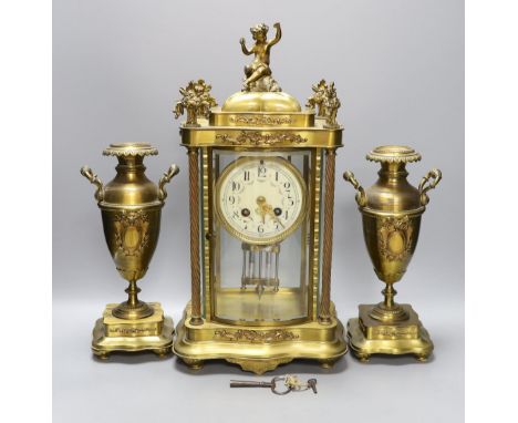 An early 20th century French brass four glass mantel clock garniture with key and pendulum, 41cm tall