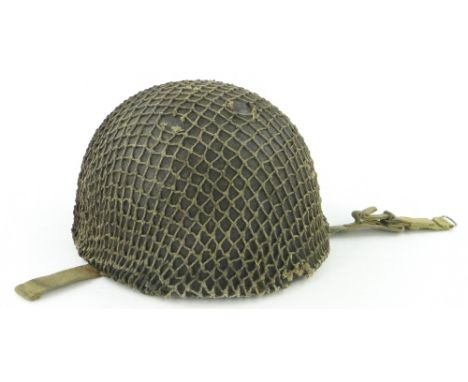 A Second World War US steel helmet 
with liner and camouflage cover.