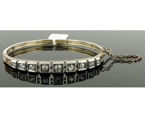 Unmarked gold hinged bangle,
set with a row of 9 graduated diamonds, total diamond content approx. 1.15cts.