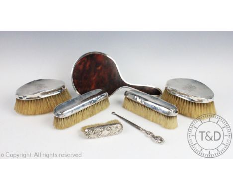 An assembled six piece silver backed dressing table set, to include: five assorted brushes, a tortoiseshell backed hand mirro