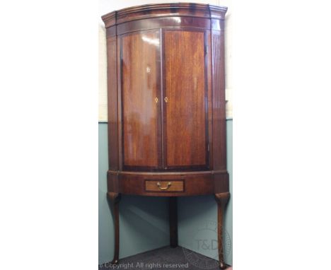 A George III inlaid oak bow front corner cabinet on later stand, of large proportions, with two doors enclosing four shelves,