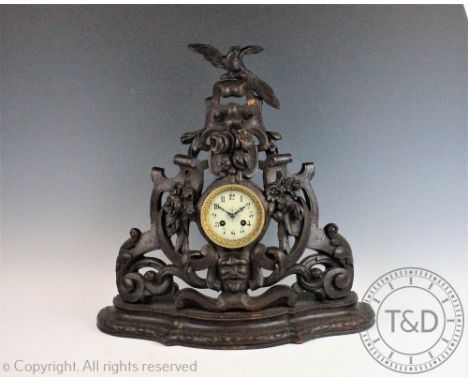 A large carved Black Forest mantel clock, the central circular face with Arabic dial within an elaborate entwined carved case