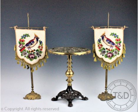 A pair of Victorian gilt brass table screens, with tapestry panels of a bird and flowers, 52cm high, with a brass and cast ir