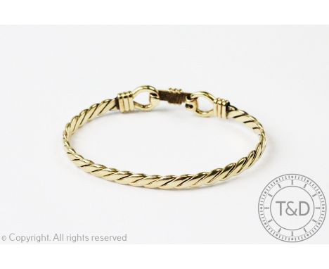 A 9ct yellow gold bangle, designed as a flattened twist with tension, snaffle-type clasp, gross weight 19.2gms  CONDITION REP