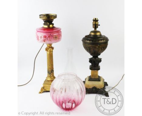 A Victorian gilt metal and pink glass oil lamp, converted to electricity, with fluted column, on scroll feet, with a foliate 