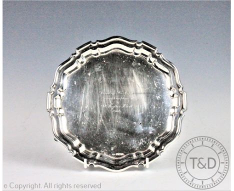 A silver waiter, Mappin and Webb, Sheffield 1905, of pie crust circular form and upon three stepped hoof feet, centrally engr