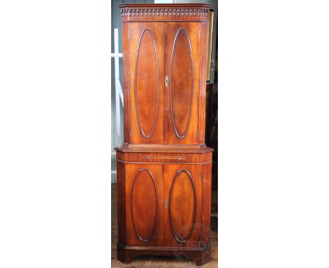 A modern George III style mahogany corner cabinet, with four oval panelled doors, on bracket feet, 173cm H x 65cm W