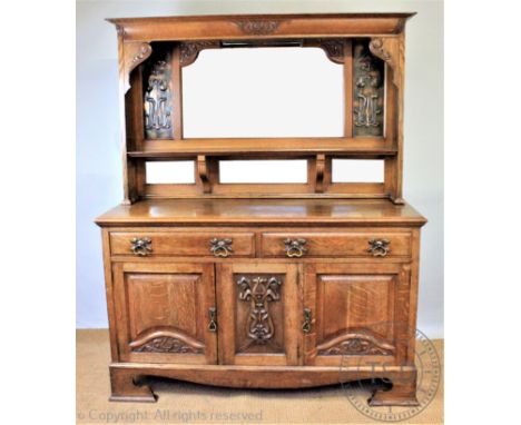 An Arts and Crafts carved golden oak high back dresser, the mirror back inset with two floral hammered copper panels, in the 