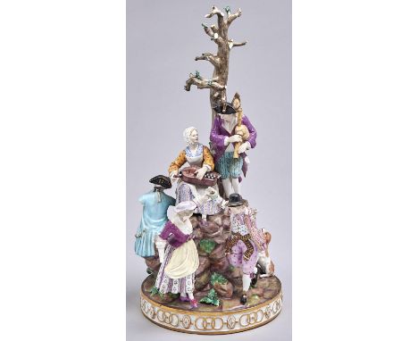 A Meissen group, c1870, of six merrymakers playing music, dancing or eating and drinking on rocks beneath a tree, the round g