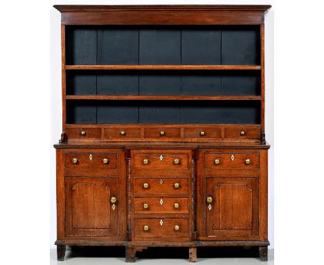 An oak dresser, North Wales, first half 19th c, the boarded rack with row of five scratch moulded spice drawers with brass kn