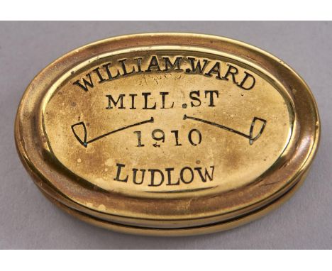 An oval brass snuff box, dated 1910, stamped with clasped hands, tobacco pipes and, in printer's type, WILLIAM WARD MILL ST L