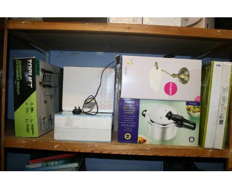 A shelf of miscellaneous; boxed pressure cooker, standing fan etc.