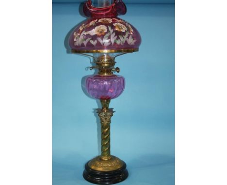 A Victorian oil lamp with cranberry coloured and floral painted shade, cranberry reservoir and barley twist stem, 71cm height