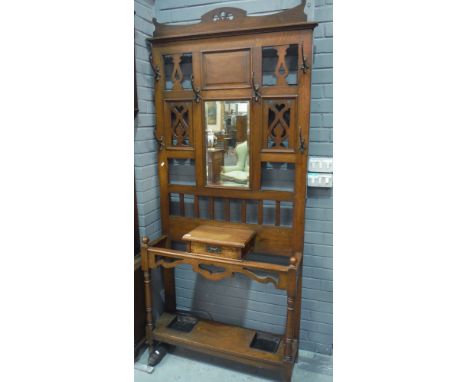 An early 20th Century oak hall stand, the pierced panel upright with six double hooks and a central mirror, above a central d