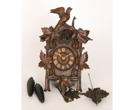 A late 19th Century Black Forest cuckoo clock in carved walnut traditional case mounted with a winged birtd, height 48cm