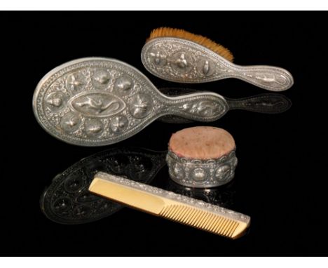 A late 19th to early 20th Century Anglo Indian white metal four piece dressing table set composed of brush, comb, hand mirror