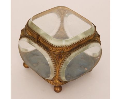 A late 19th Century gilt metal mounted bevelled glass casket of cushion form, the hinged cover above a blue buttoned lined ba