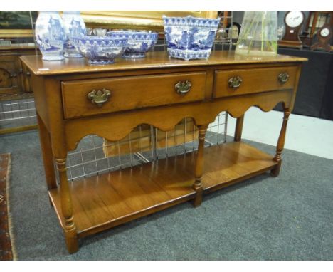 A 17th Century style light oak two drawer dresser fitted with two drawers above a shaped apron on turned legs united by a pot