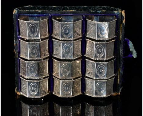 A cased set of twelve hallmarked silver hexagonal napkin rings each numbered and decorated with foliate engraved and engine t