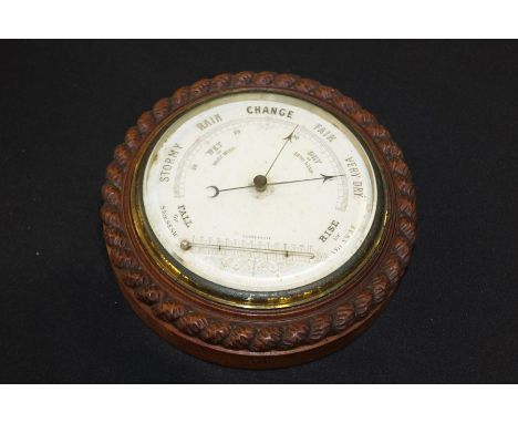 Oak barometer and thermometer. with a carved rope twist edge and white enamel dial