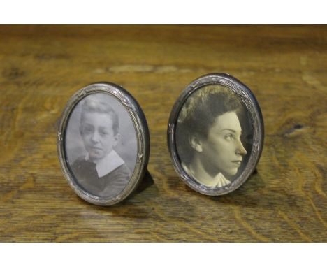 Pair of white metal oval picture frames, with reeded tied ribbon borders and easel backs, 6cm x 8cm
