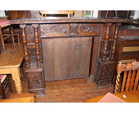 An early 20th Century Jacobean style oak fire surround, lunette moulding to edge, pillared sides, 135cm high