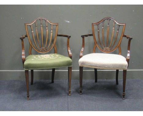 A pair of Hepplewhite style mahogany open armchairs with shield shaped backs, outscrolling arms and tapered legs (upholstery 