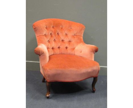 An early Victorian peach upholstered button back armchair the outswept arms on cabriole legs